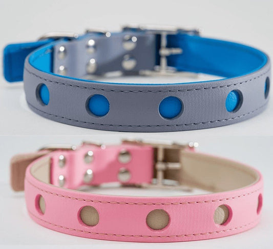 Two leather dog collars, one gray with blue lining and one pink with beige lining. Both have silver hardware and decorative holes.